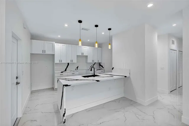 a view of a kitchen with kitchen island a sink stainless steel appliances and cabinets
