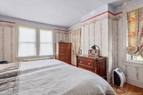 a bedroom with a bed and a dresser with a large window