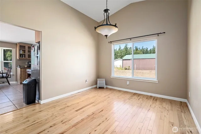 a view of an empty room with window and wooden floor