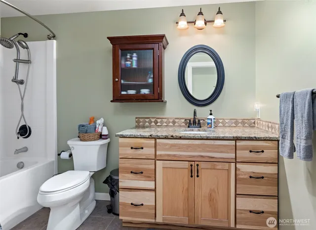 a bathroom with a granite countertop toilet a sink and a mirror