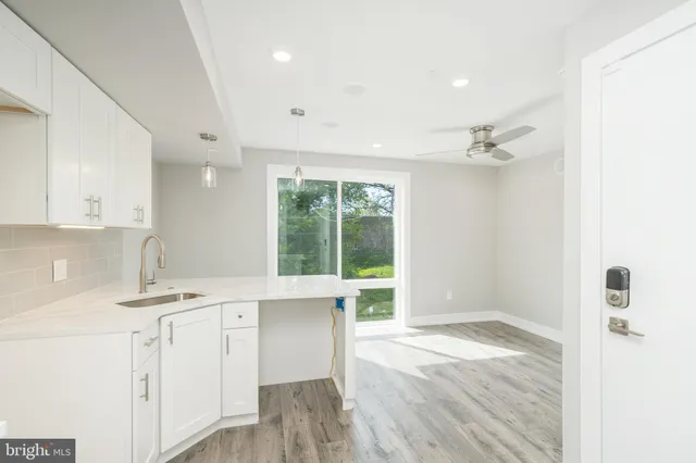 a view of a kitchen with a sink wooden cabinets and wooden floor