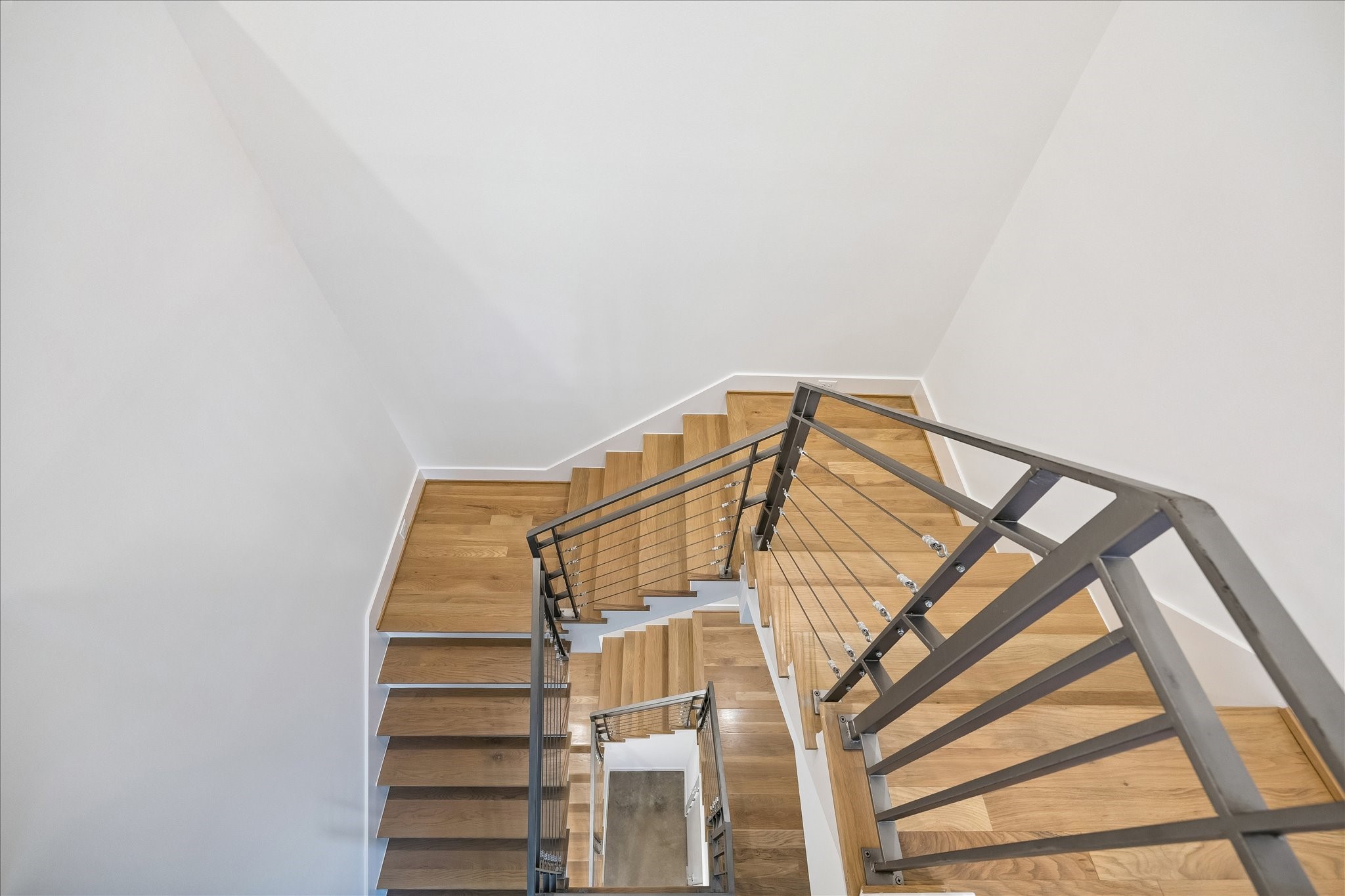 2147 Harold Street Houston, TX 77098 - Photo 22 of 28 Staircase to Third Level: Architectural open-riser staircase with wood treads and sleek metal railing, leading to the third-floor landing and elevator shaft access on each level.