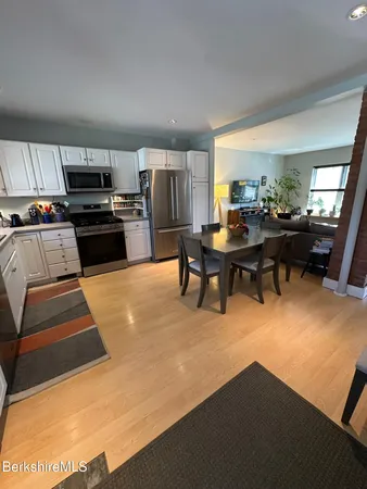 a living room with stainless steel appliances furniture a kitchen view and a dining table