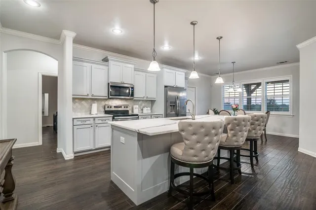 a dining table chair wooden floor a refrigerator a kitchen island and stools in a kitchen