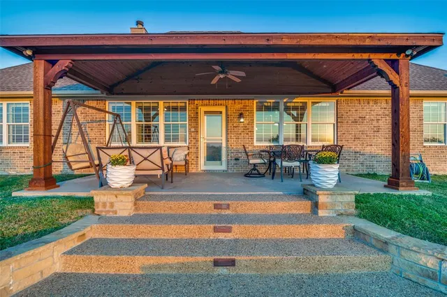 a view of a patio with a table and chairs under an umbrella with a barbeque