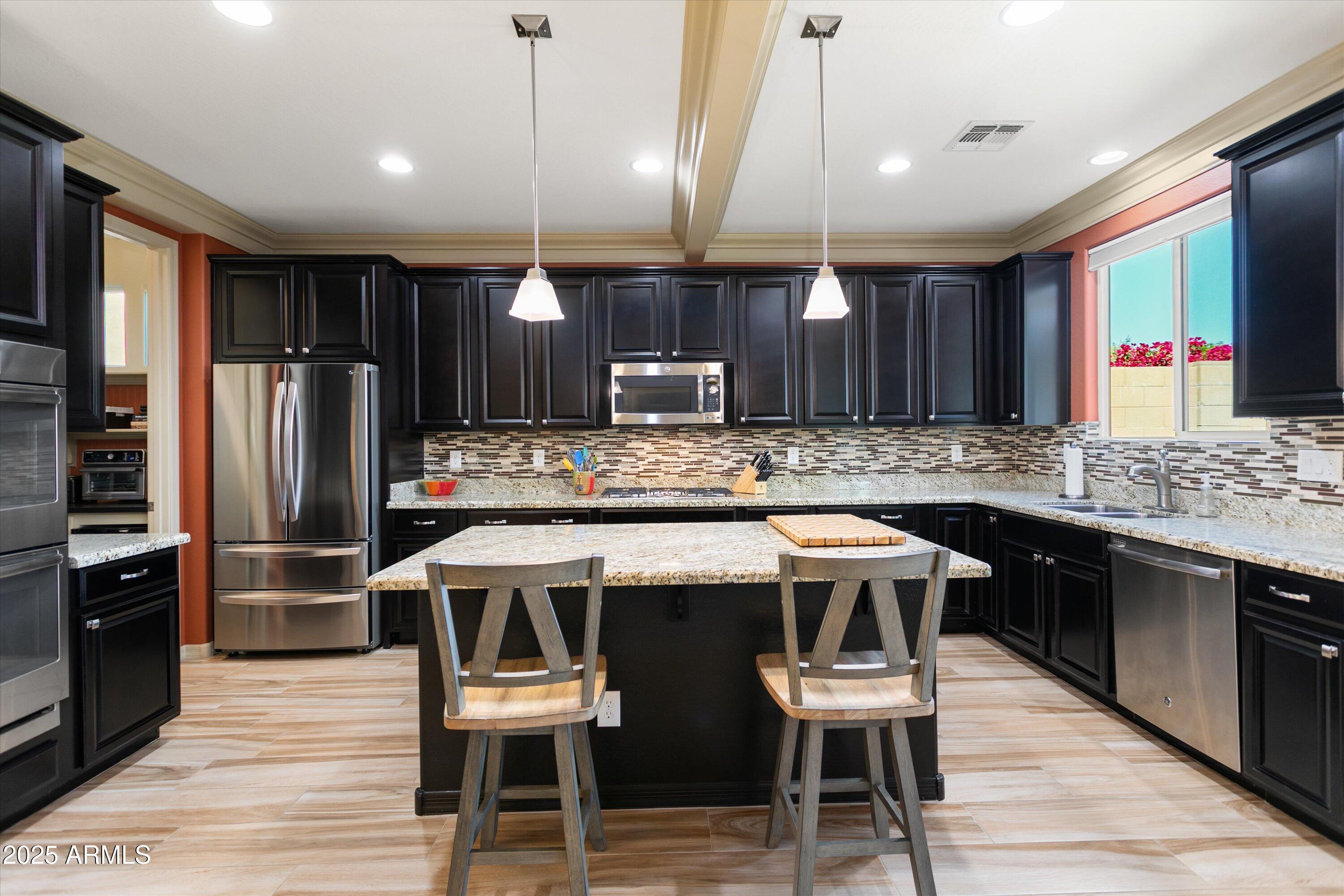 3197 North Springfield Street Buckeye, AZ 85396 - Photo 14 of 60 a kitchen with stainless steel appliances a table chairs refrigerator and cabinets
