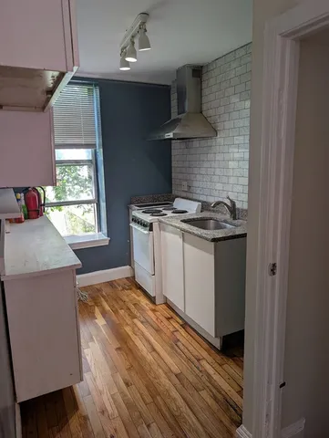a kitchen with a stove and a wooden floor