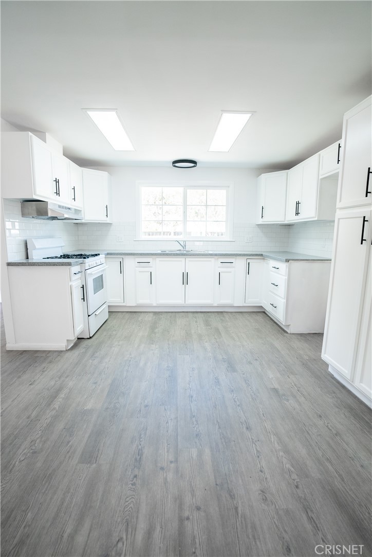 a large kitchen with cabinets wooden floor and a sink