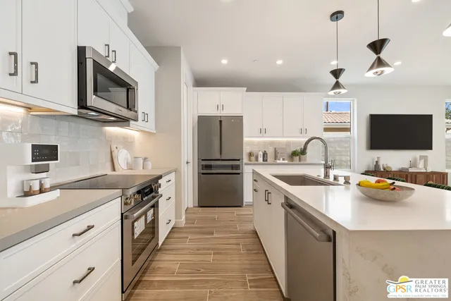 a kitchen with stainless steel appliances granite countertop a sink a stove a refrigerator and island with wooden floor