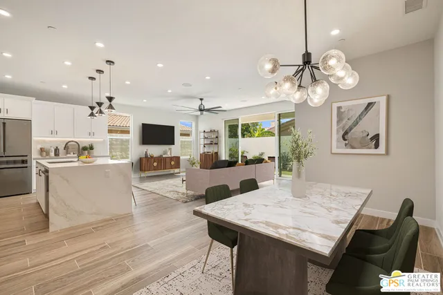 a view of a dining room with furniture a kitchen and chandelier