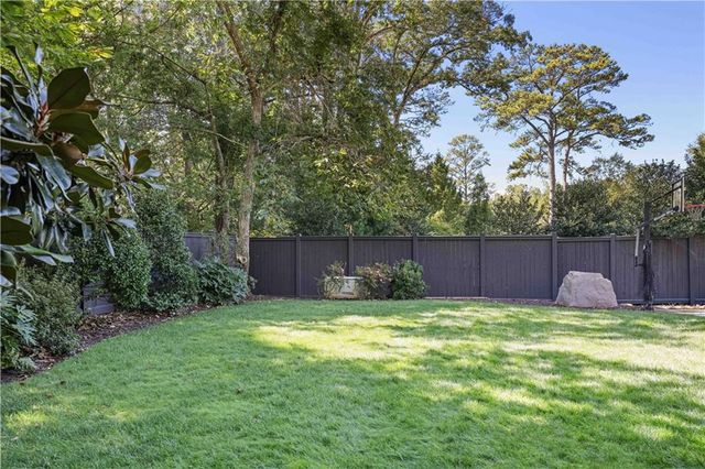 a view of a big house with a big yard plants and large trees
