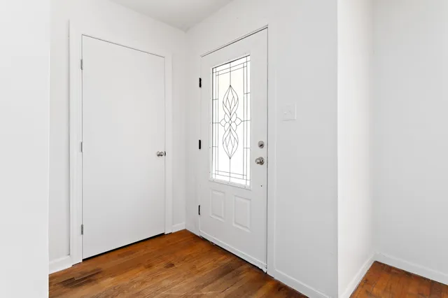 a view of an empty room with wooden floor and closet