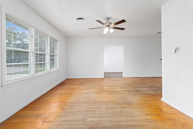 a view of an empty room with wooden floor and window