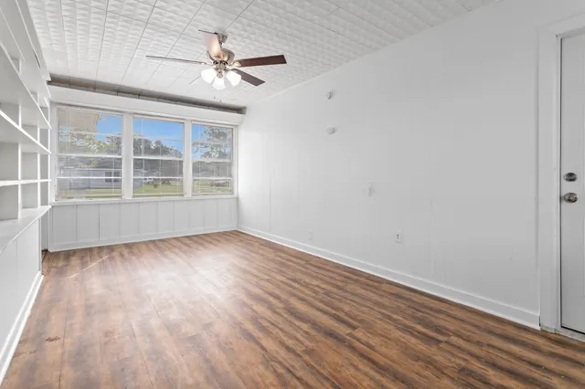 an empty room with wooden floor and windows