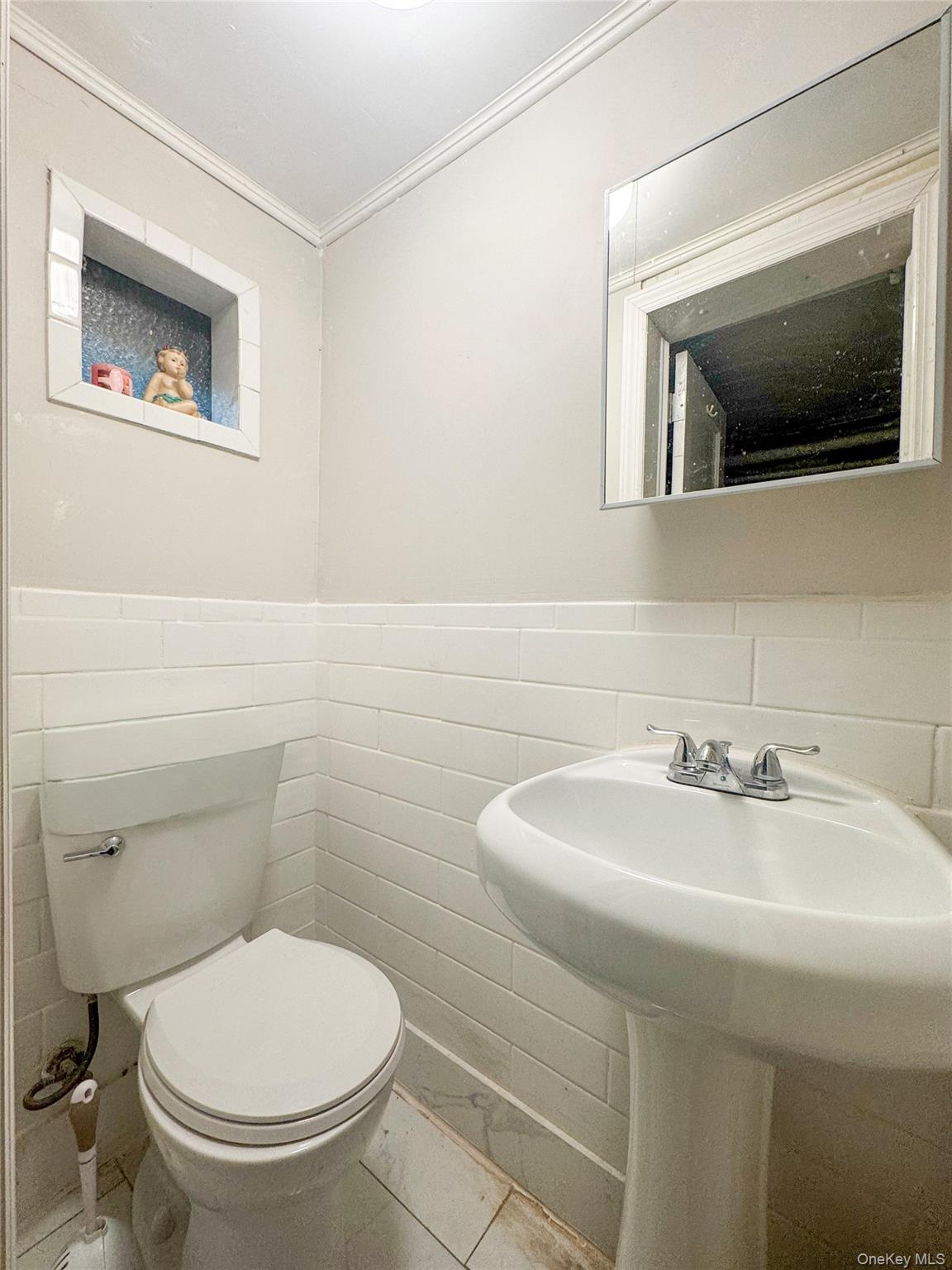 2440 Morgan Avenue Bronx, NY 10469 - Photo 18 of 23 Half bath featuring tile walls, a wainscoted wall, ornamental molding, and tile patterned flooring