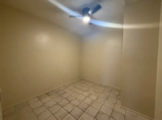 a view of an empty room and chandelier fan