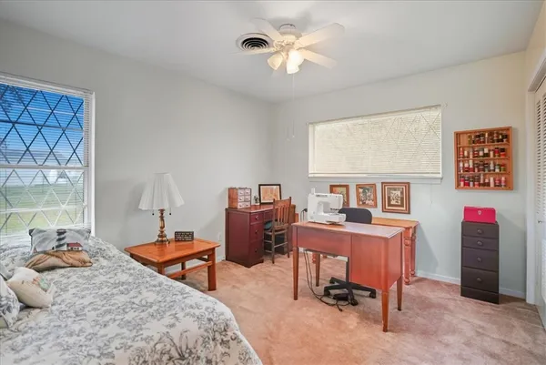 a bedroom with a bed a desk and chair with window