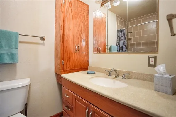 a bathroom with a granite countertop sink a toilet and shower