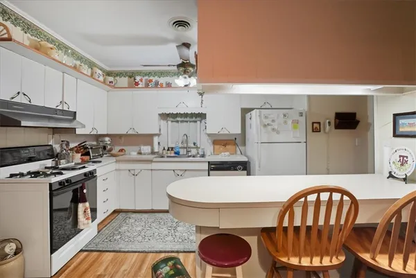 a kitchen with stainless steel appliances granite countertop a stove a sink dishwasher and cabinets with wooden floor