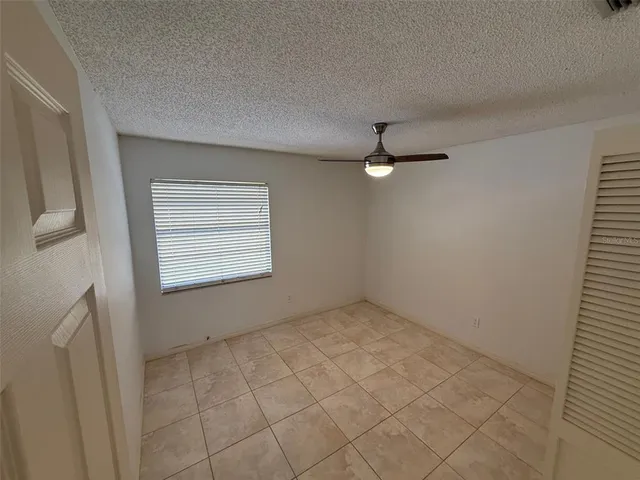 an empty room with windows and fan