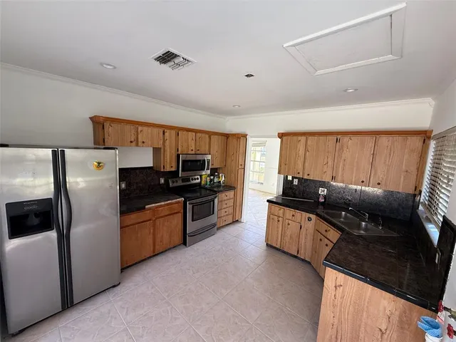 a kitchen with granite countertop a refrigerator stove top oven and sink