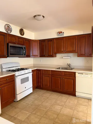 a kitchen with granite countertop a sink a stove top oven and cabinets