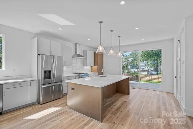 a kitchen with stainless steel appliances granite countertop a sink a stove and a wooden floors