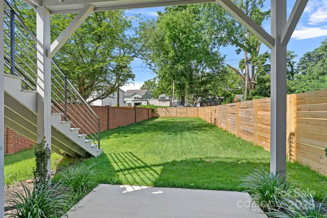 a view of a backyard with plants and large trees