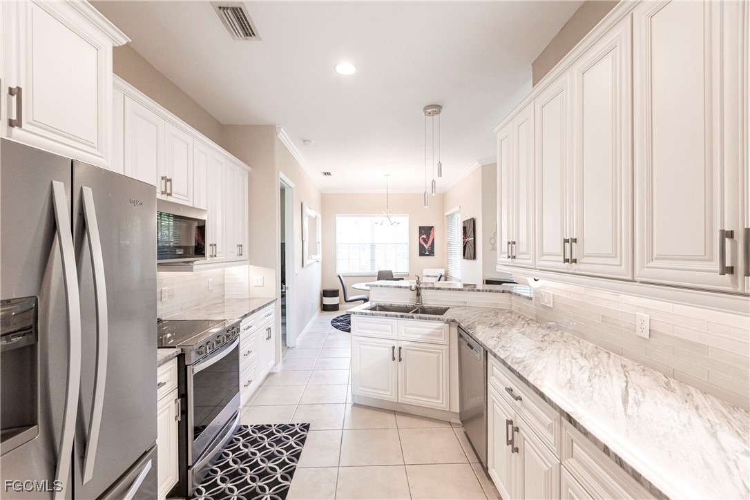 9013 West Ridge Court Fort Myers, FL 33912 - Photo 14 of 43 a kitchen with stainless steel appliances granite countertop a sink a stove a refrigerator and cabinets