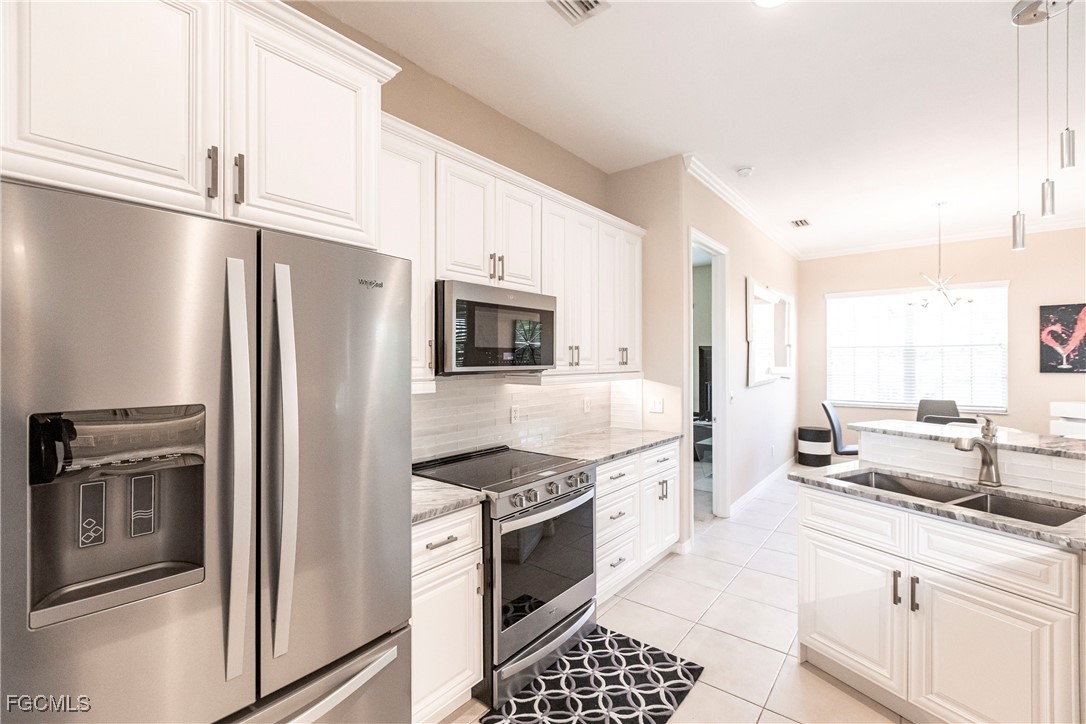 9013 West Ridge Court Fort Myers, FL 33912 - Photo 16 of 43 a kitchen with stainless steel appliances granite countertop a refrigerator a stove and white cabinets