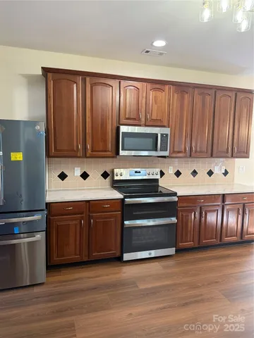 a kitchen with stainless steel appliances granite countertop a stove microwave and cabinets