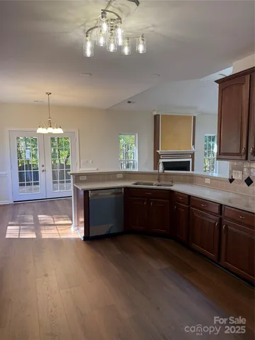 a kitchen with stainless steel appliances granite countertop a sink dishwasher a stove a dining table and chairs with wooden floor
