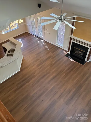an empty room with wooden floor fireplace and windows