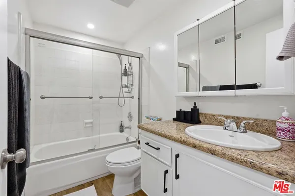 a bathroom with a granite countertop sink toilet and shower