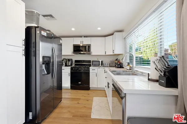 a kitchen with stainless steel appliances granite countertop a refrigerator a sink a stove top oven a sink dishwasher and wooden cabinets