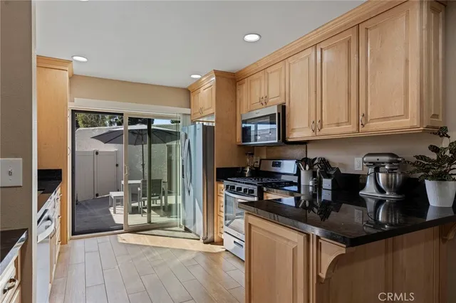 a kitchen with stainless steel appliances granite countertop a refrigerator a sink and white cabinets