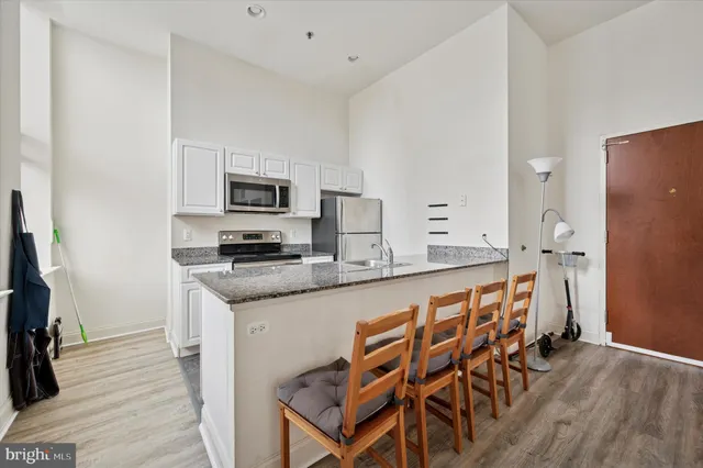 a kitchen with granite countertop a refrigerator and a stove top oven