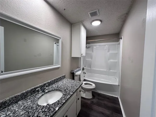 a bathroom with a granite countertop sink toilet mirror and bathtub