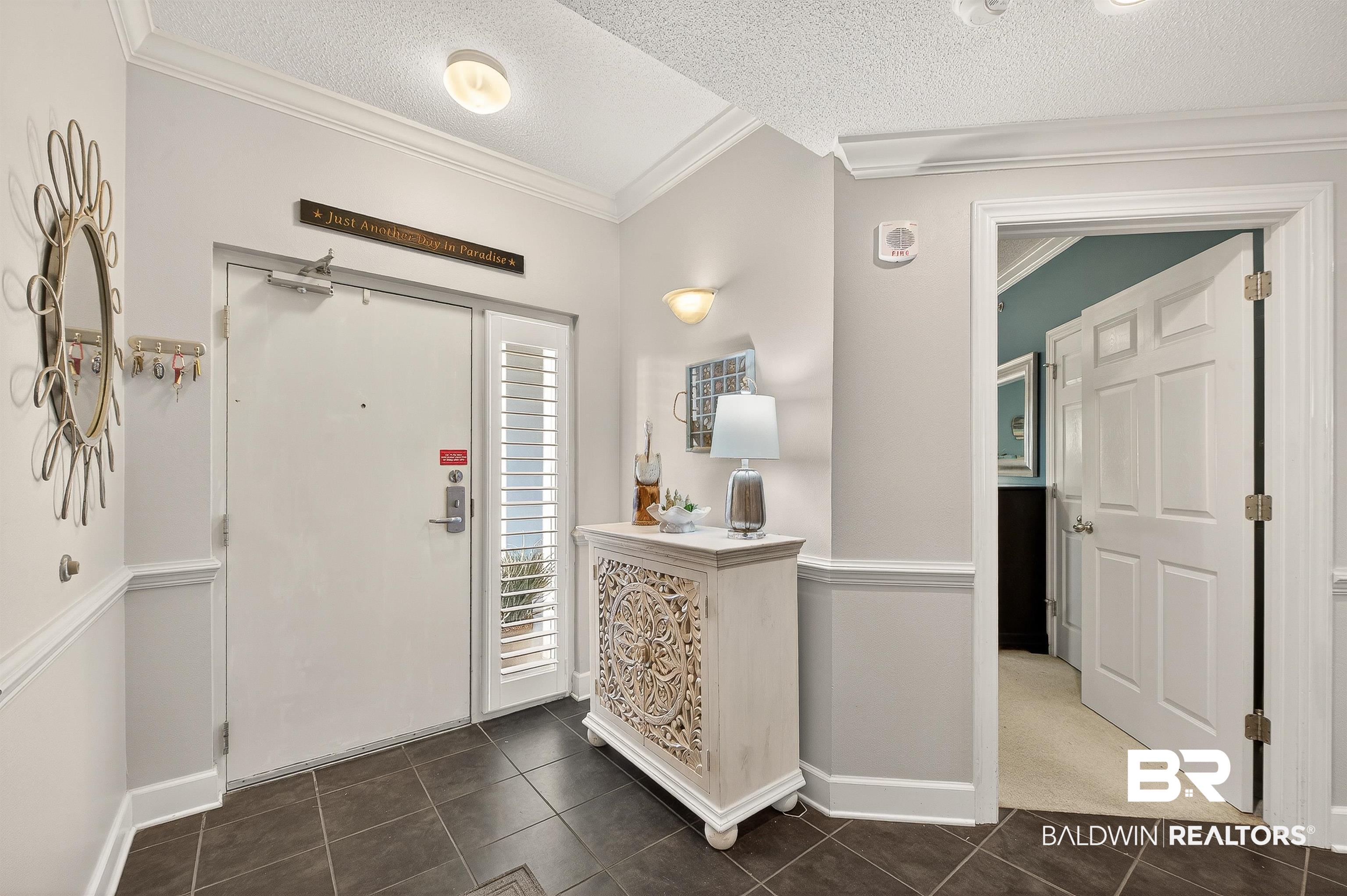 27582 Canal Road, Unit 2507 Orange Beach, AL 36561 - Photo 7 of 75 Entryway with a textured ceiling, ornamental molding, and dark tile patterned floors