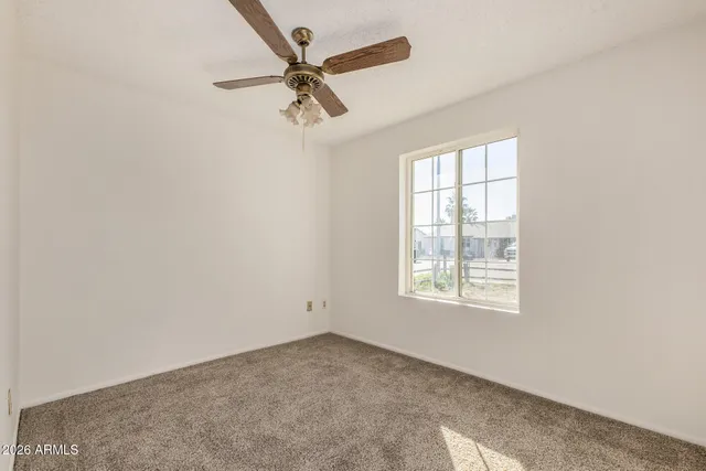an empty room with a window and a fan