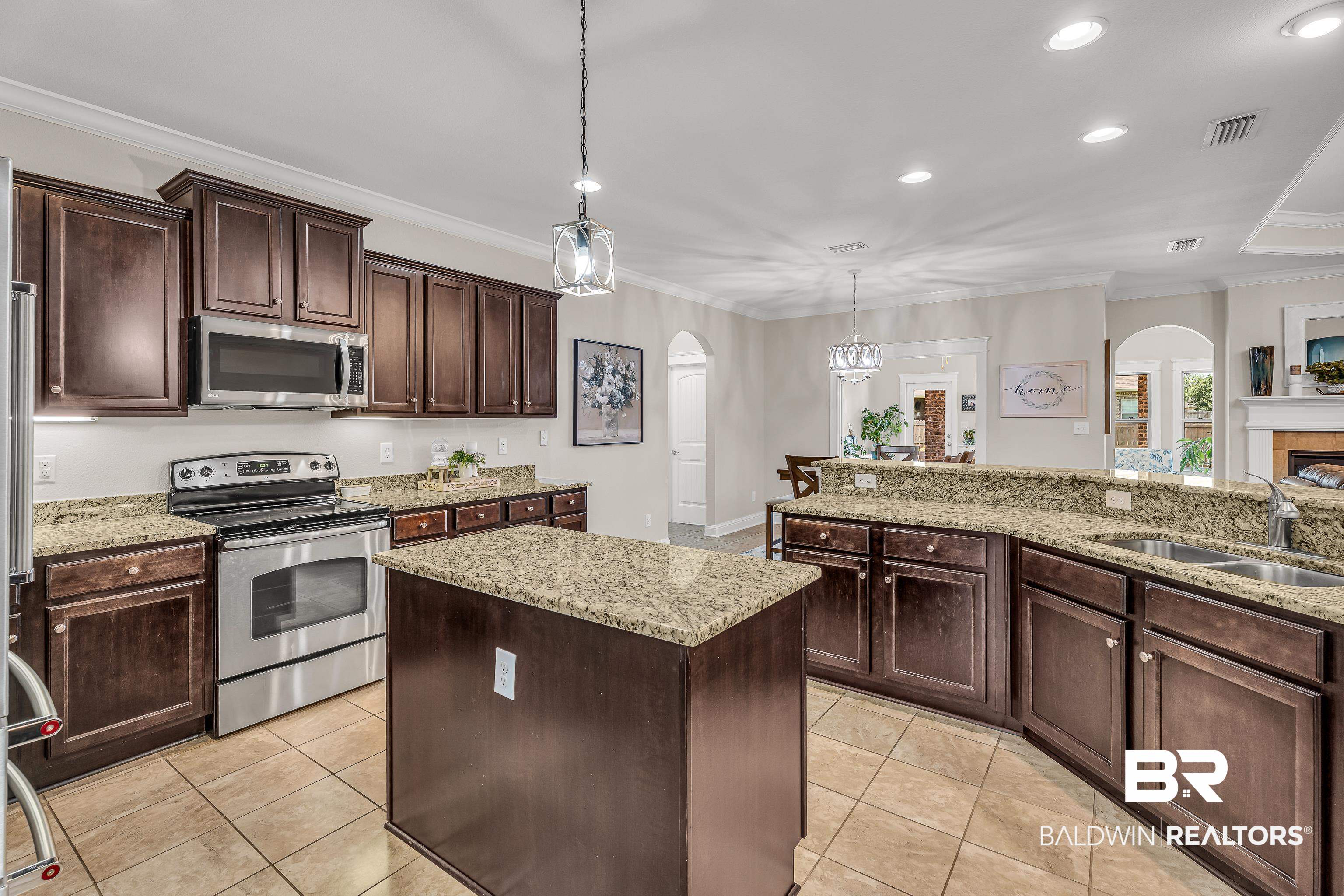 9675 Camberwell Drive Daphne, AL 36526 - Photo 12 of 34 Kitchen with appliances with stainless steel finishes, arched walkways, crown molding, light tile patterned floors, and a center island