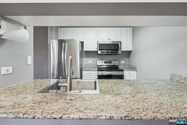 a kitchen with stainless steel appliances kitchen island granite countertop a refrigerator stove and oven