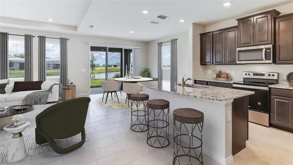 a kitchen with granite countertop a table chairs stove and refrigerator