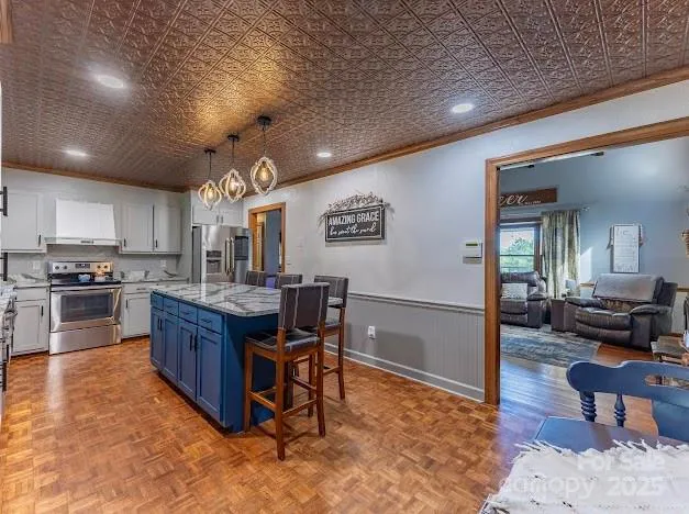 a kitchen with stainless steel appliances granite countertop a stove refrigerator a dining table and chairs with wooden floor