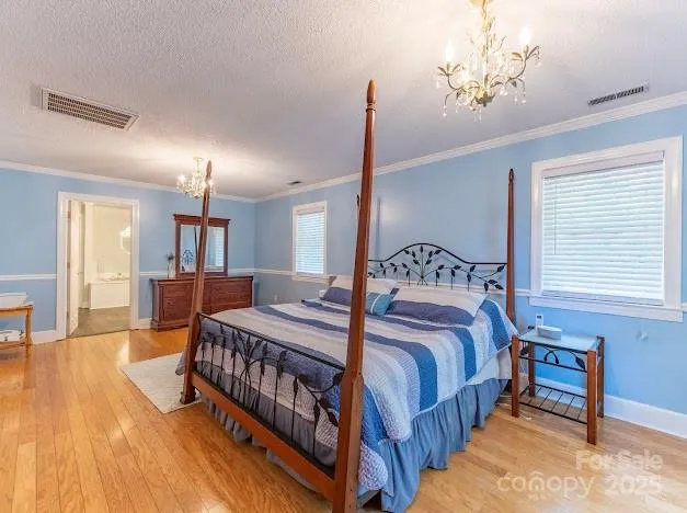a bedroom with a bed a chandelier and dresser
