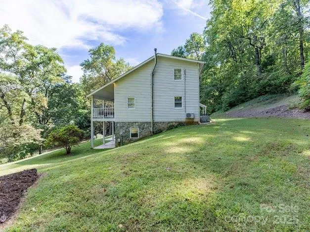 a backyard of a house with plants and large tree