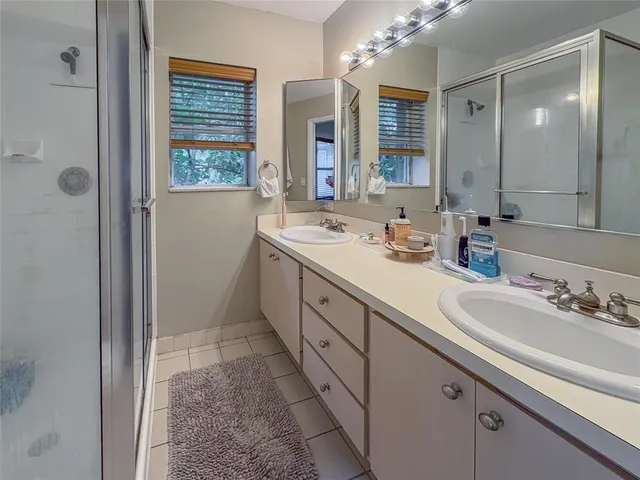 a spacious bathroom with a double vanity sink a mirror and a shower