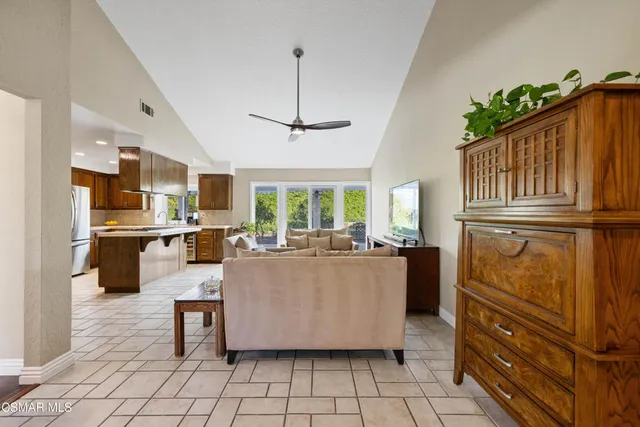 a living room with couches a dining table kitchen appliances and a counter top space