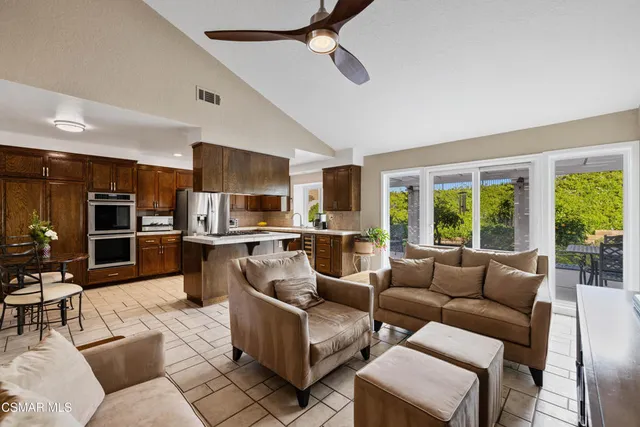 a living room with furniture kitchen view and a large window