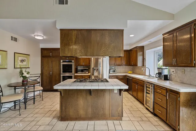 a kitchen with stainless steel appliances granite countertop a stove top oven a sink dishwasher and a refrigerator